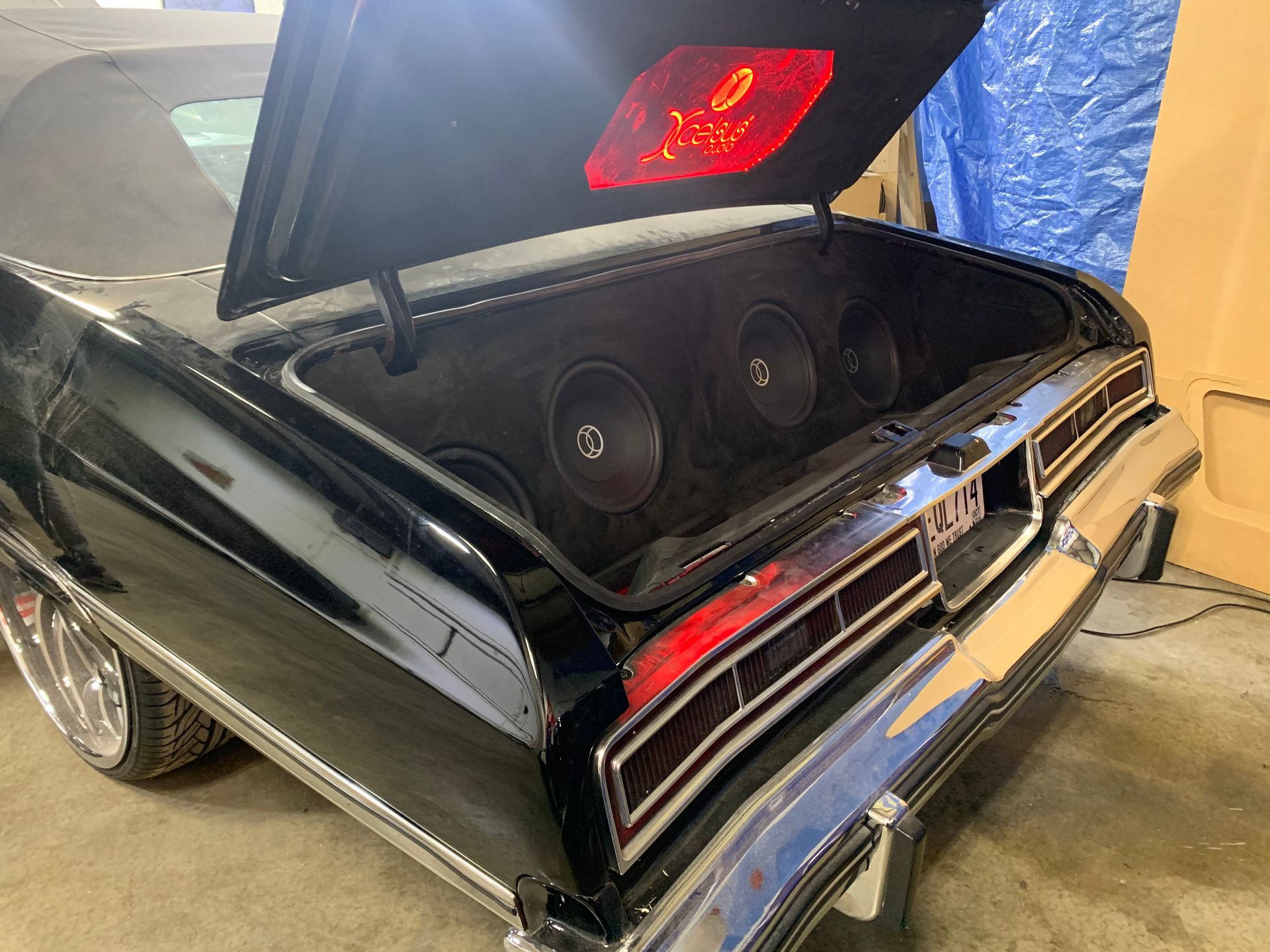 A black car with the trunk open and speakers in it.