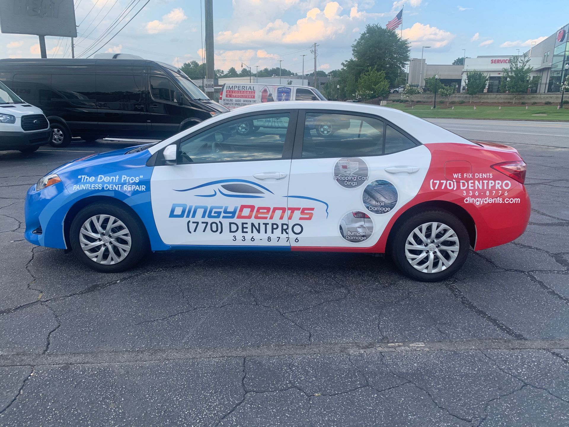A red, white and blue car is parked in a parking lot.