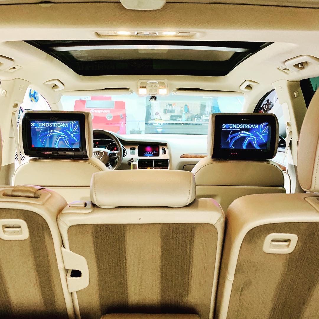 The back seat of a car with two headrest monitors.