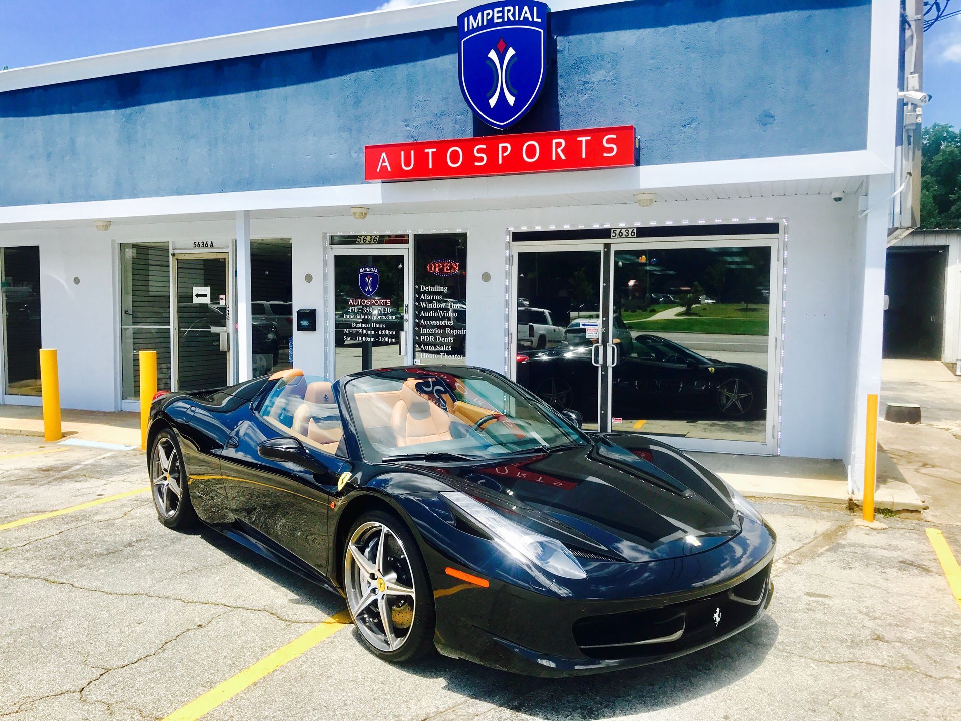A black sports car is parked in front of a building that says Autosports
