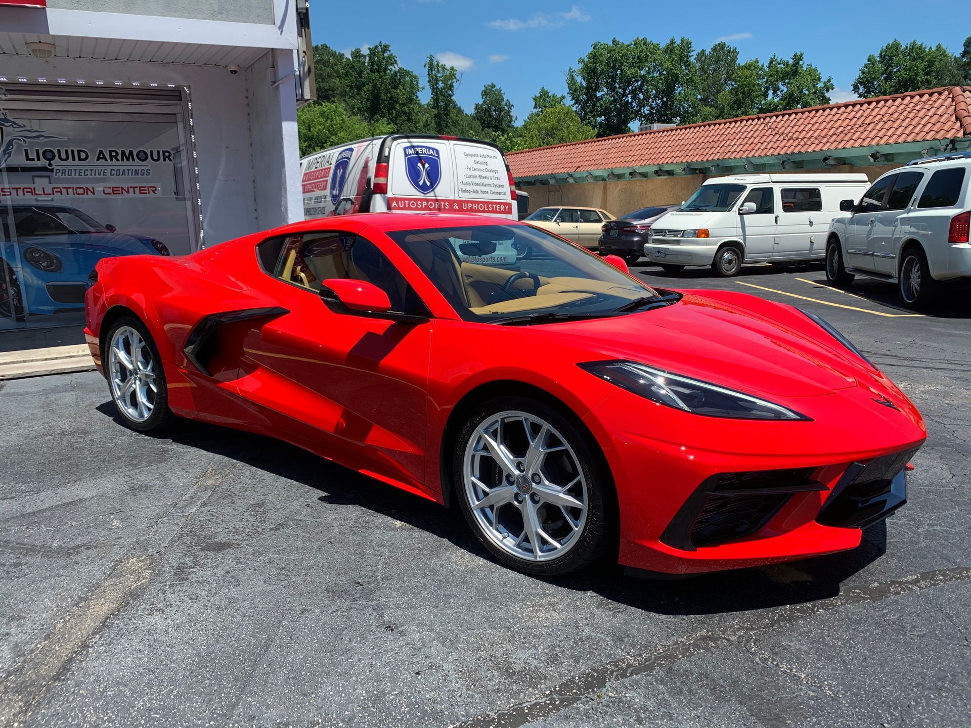 A red sports car is parked in a parking lot in front of a building.