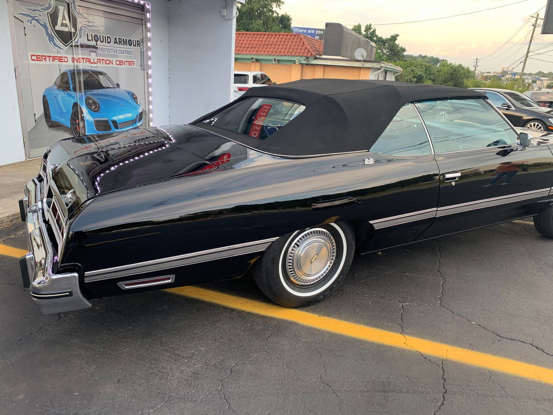 A black convertible car is parked in a parking lot.