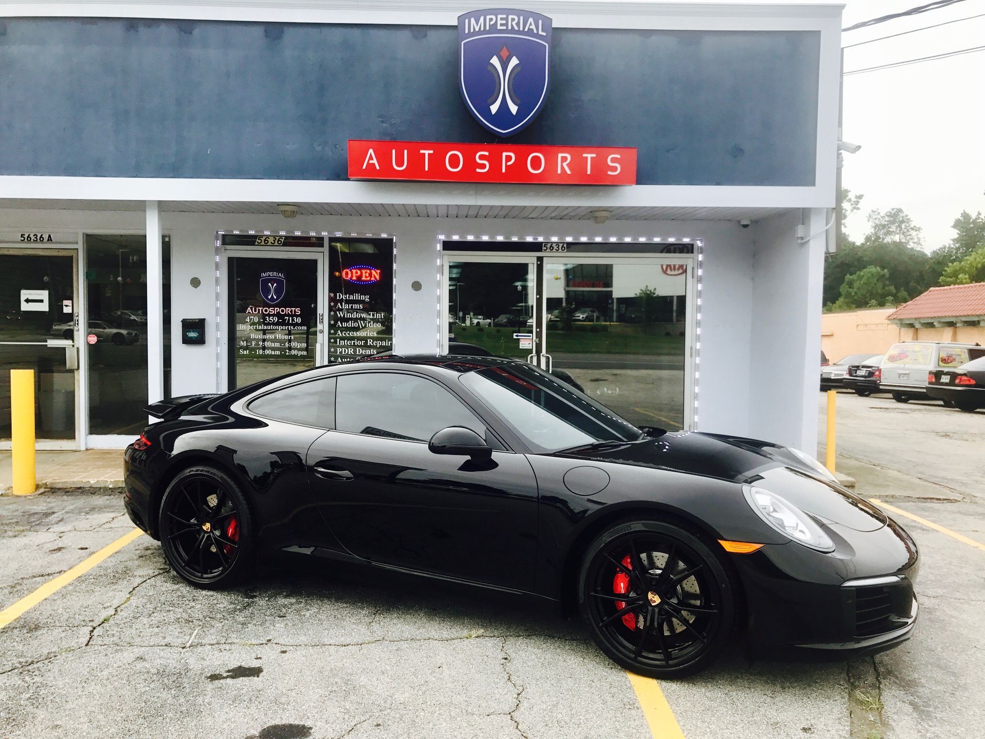 A good-looking black sports car is parked in front of an auto sports store