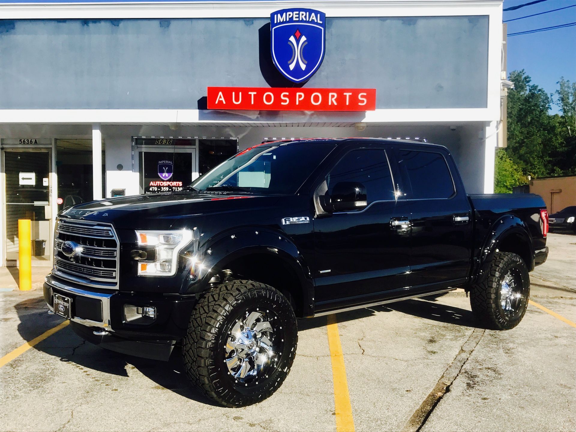 A black truck is parked in front of an auto sports store