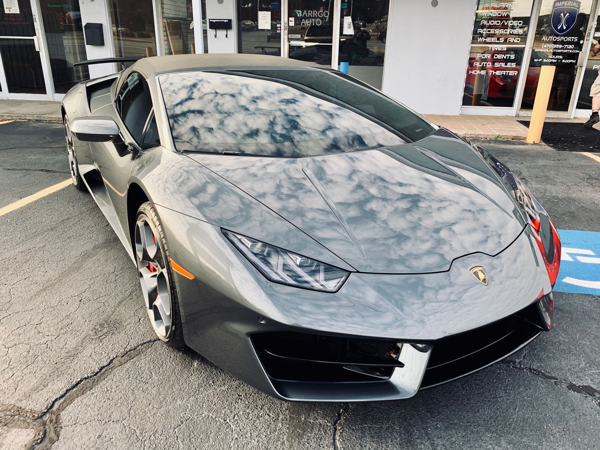 A gray Lamborghini Huracan is parked in a handicapped parking spot.