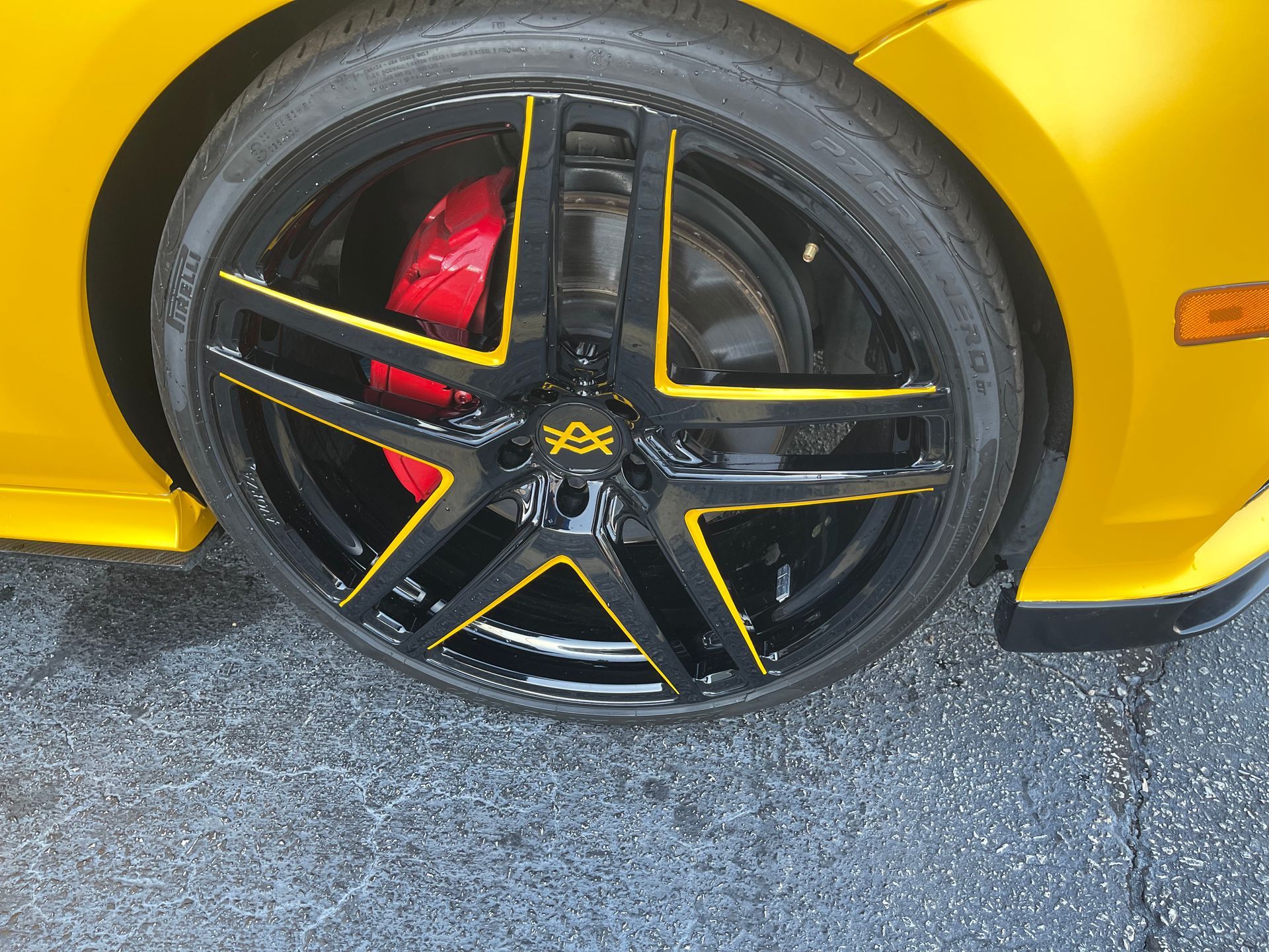 A yellow car with black wheels and a red brake pad