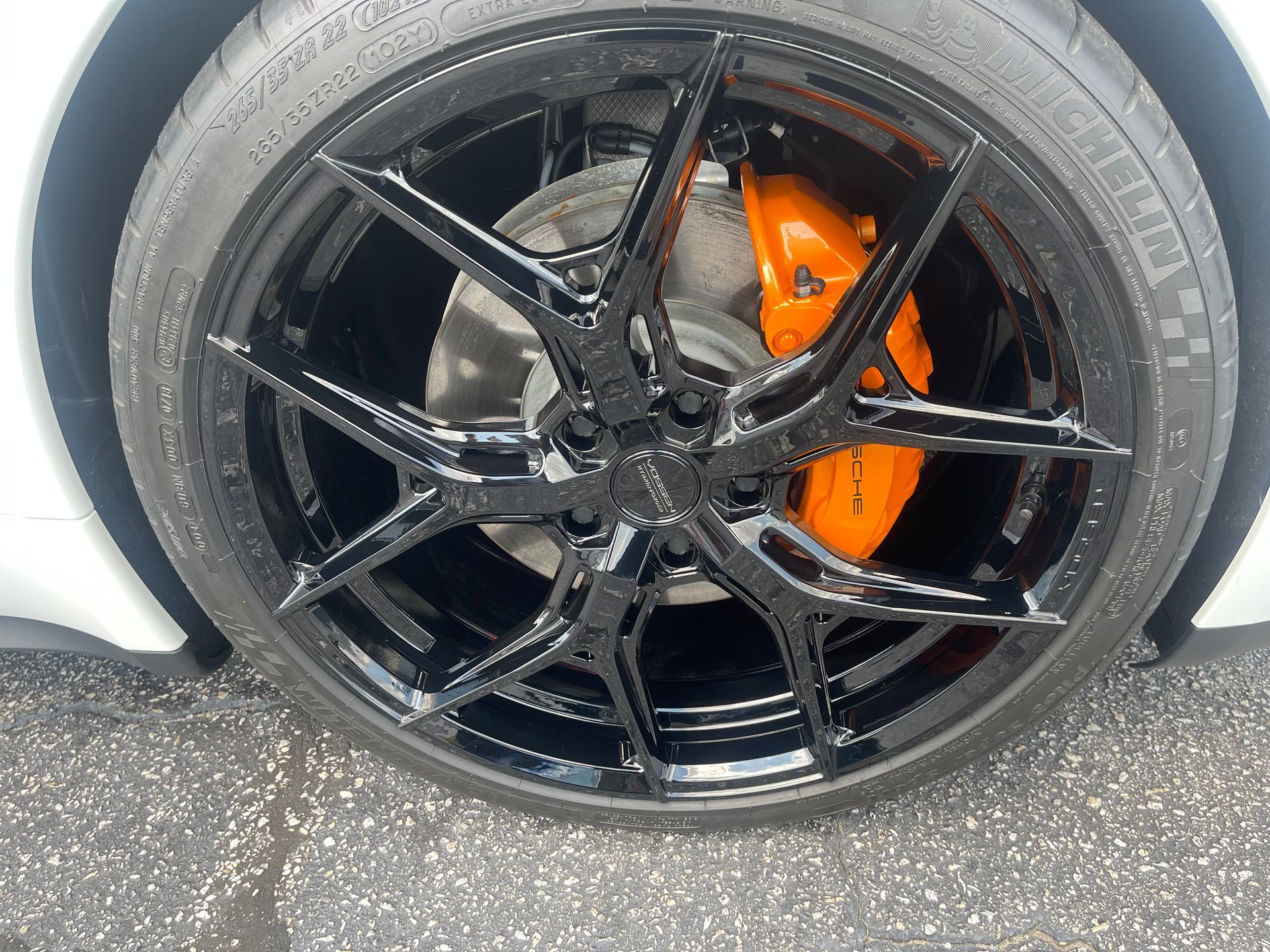A close-up of a car wheel with orange brake calipers