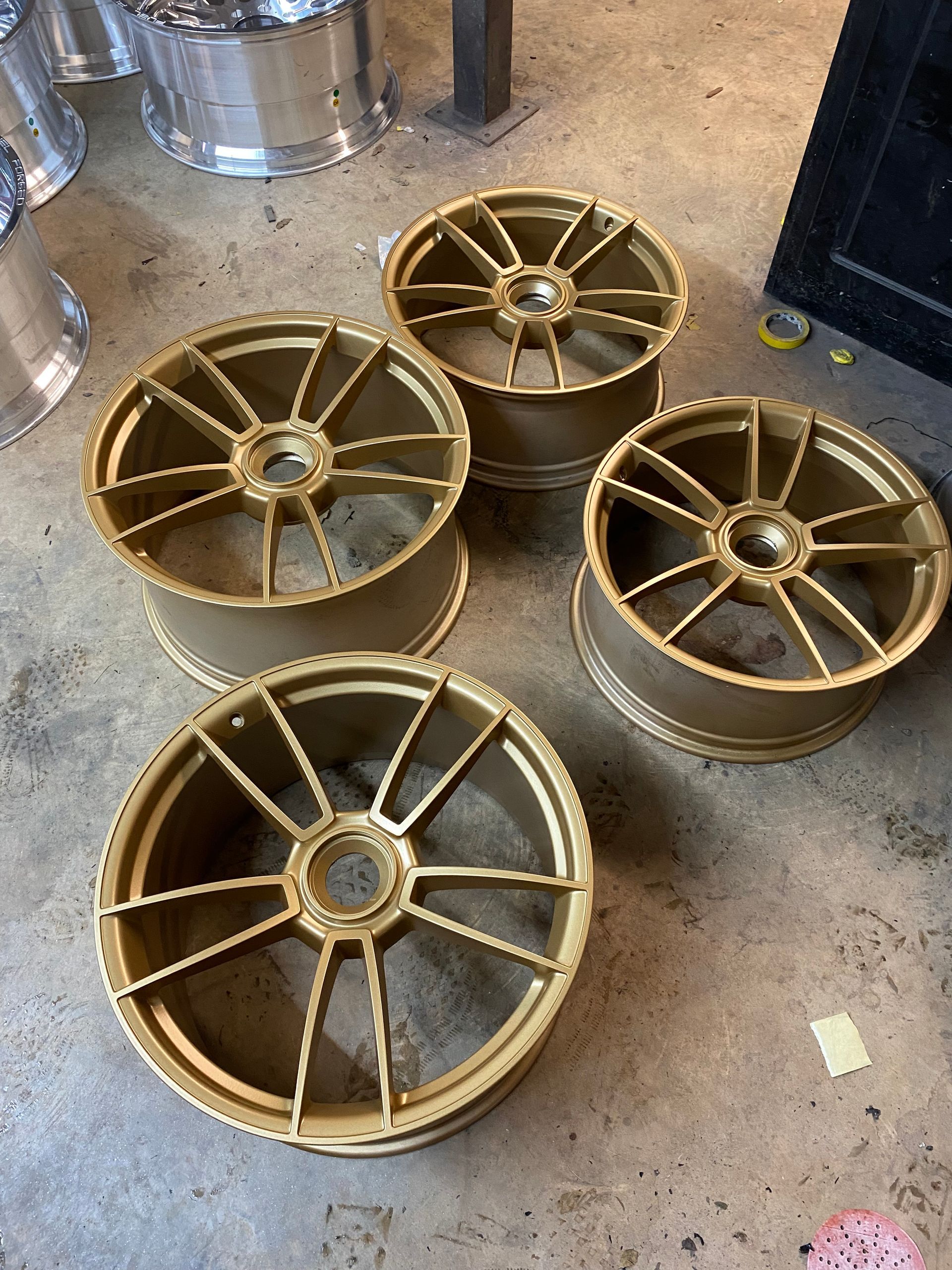 Four gold wheels are sitting on a concrete floor.