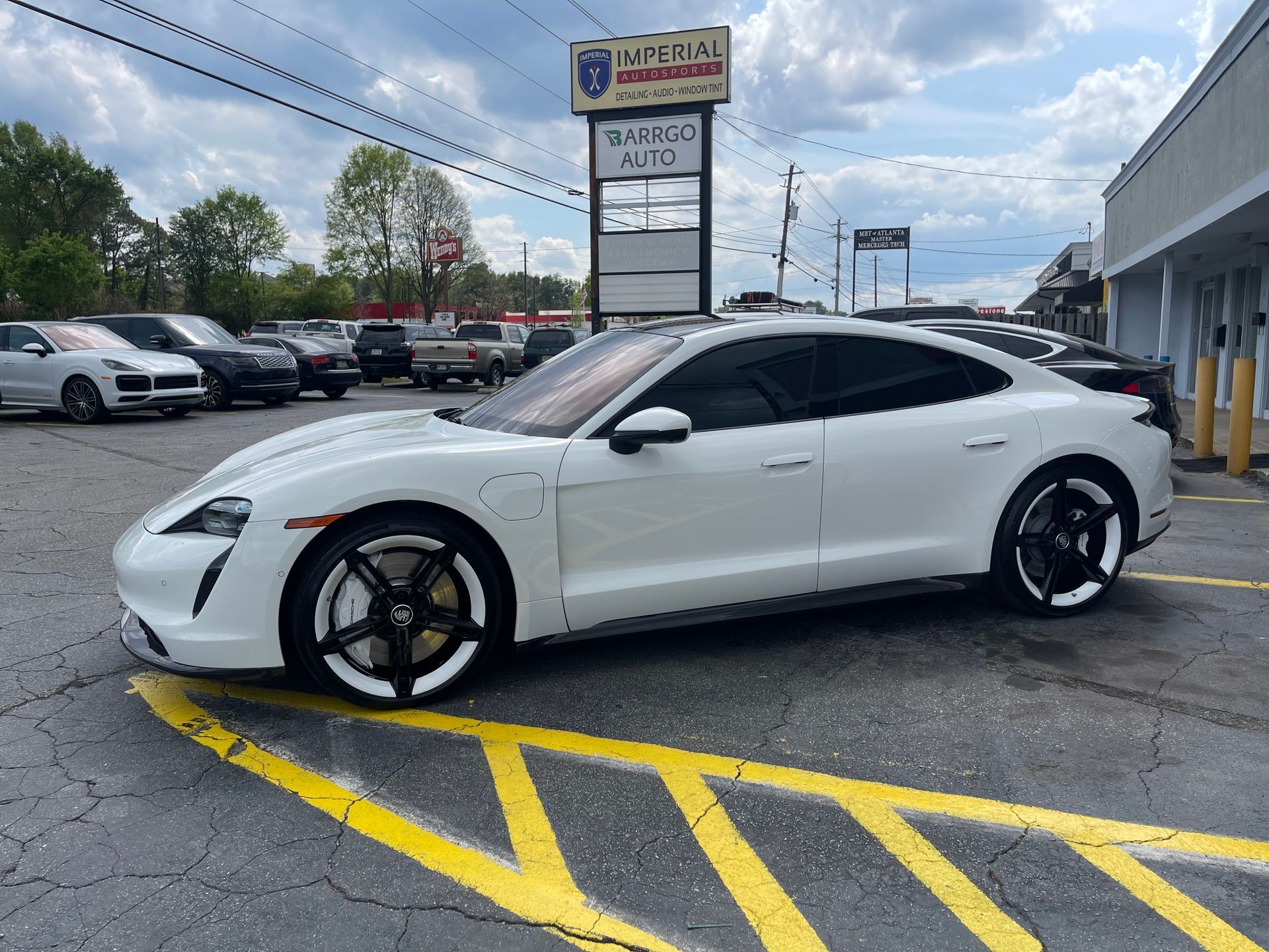 A white Porsche is parked in a parking lot.