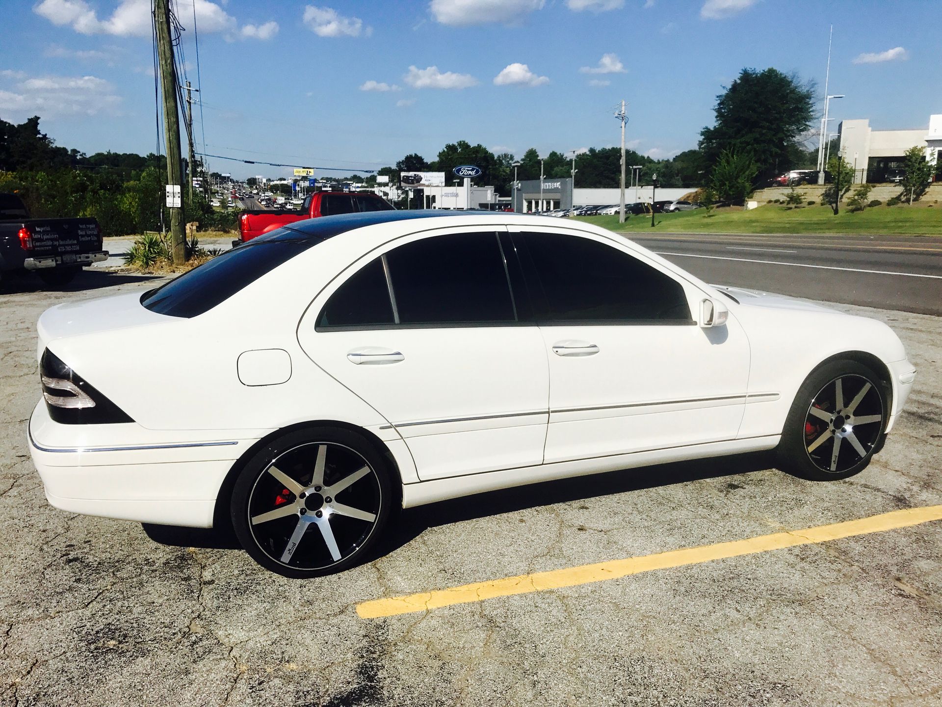 A white car with black wheels is parked in a parking lot