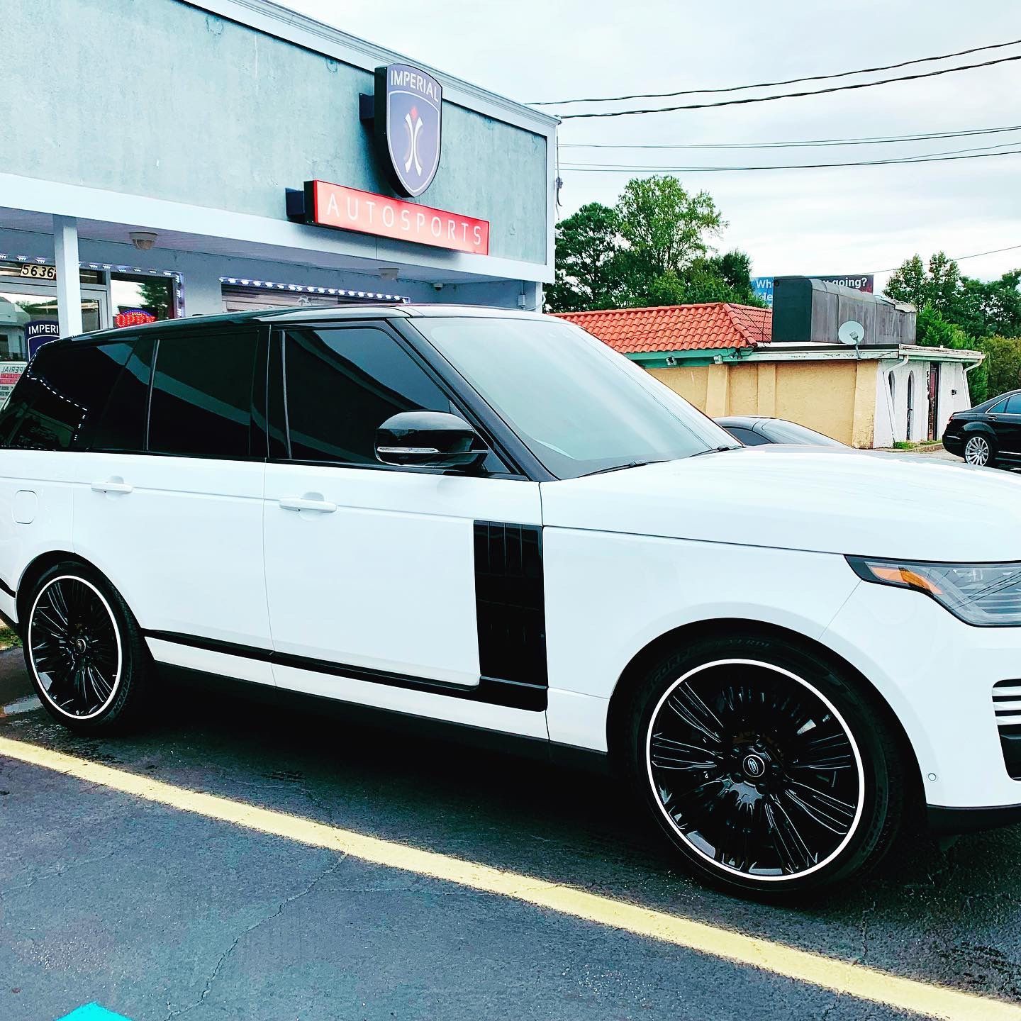 A white Range Rover is parked in a parking lot in front of a building.