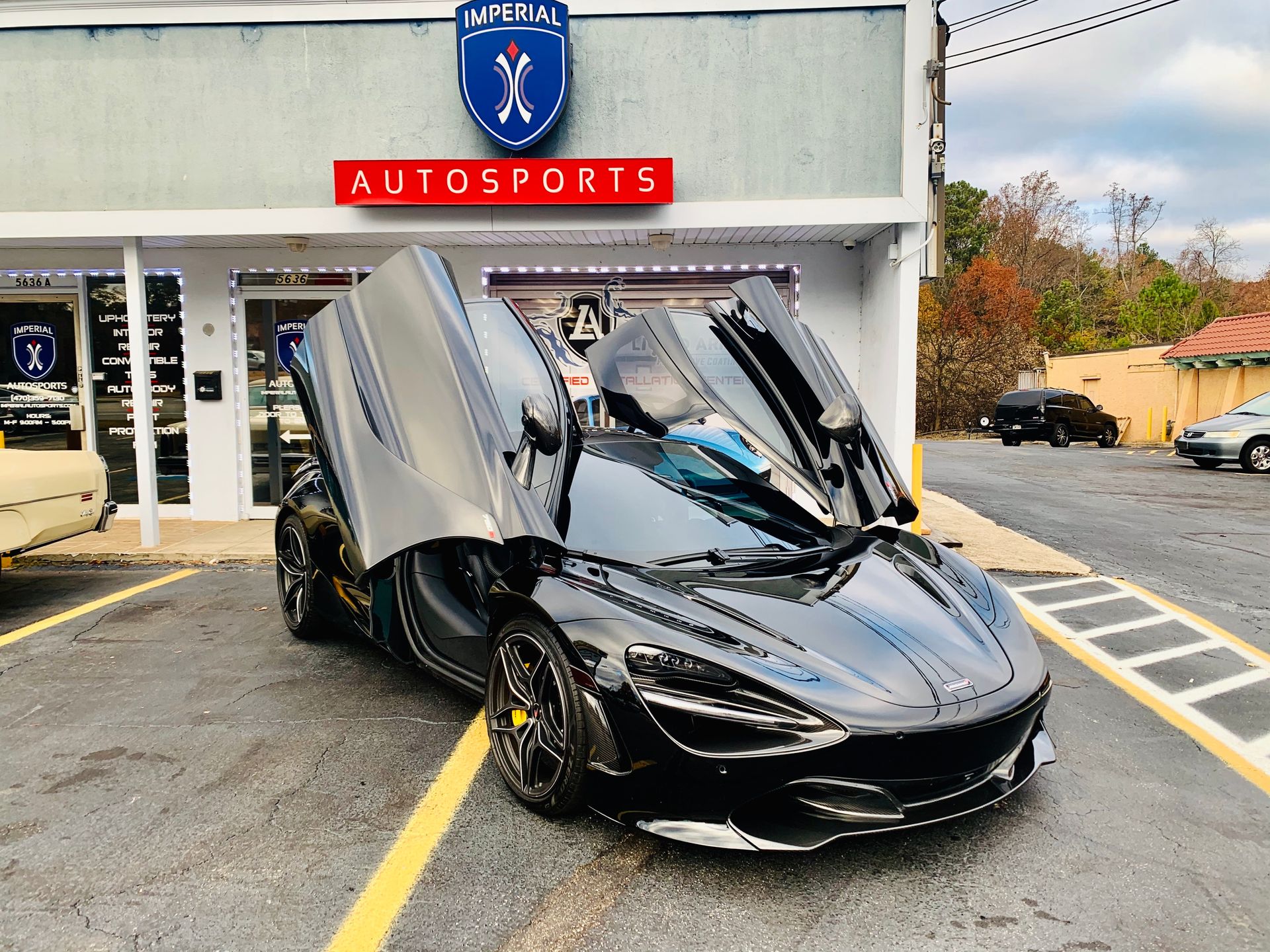 A black sports car is parked in front of a car dealership.