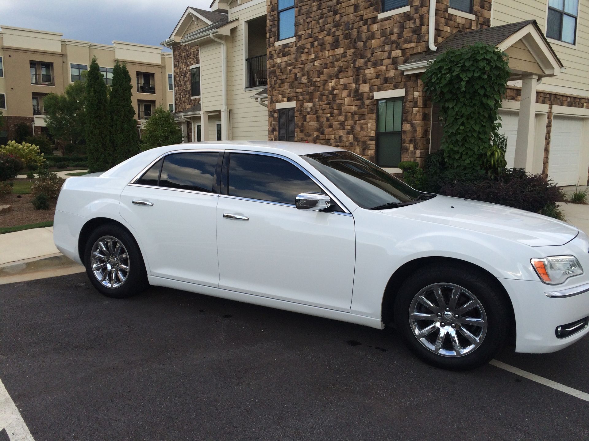 A white car is parked in front of a stone building.