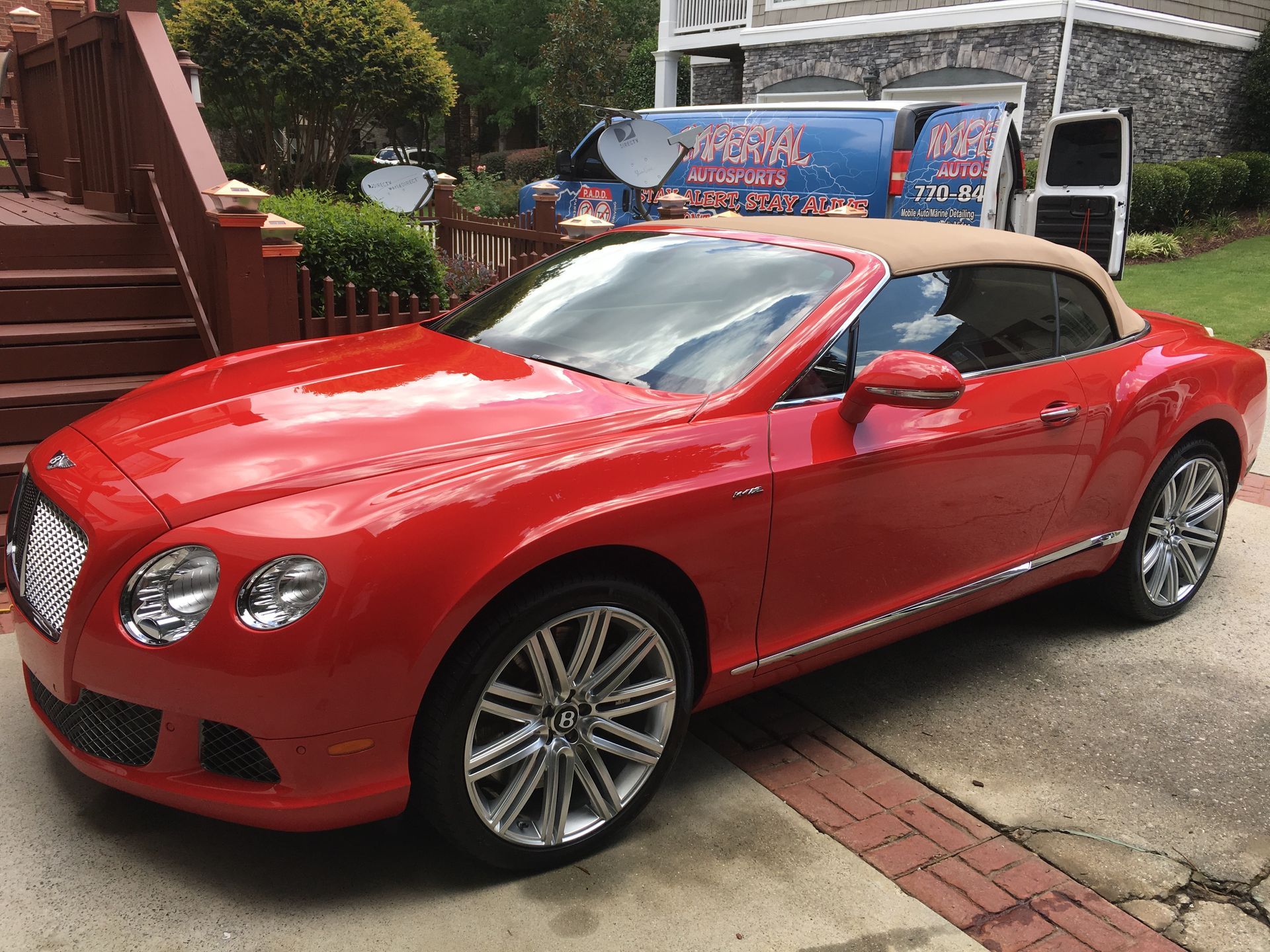 A red Bentley Convertible is parked in front of a house.