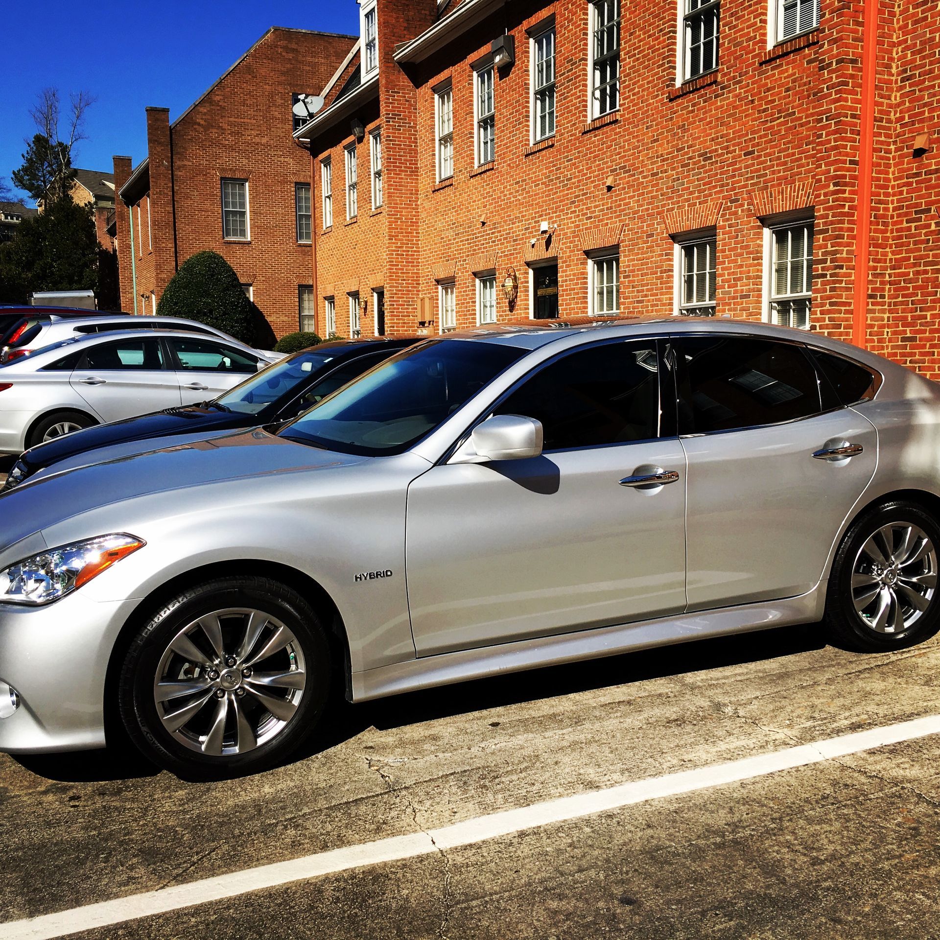 A silver car is parked in front of a brick building