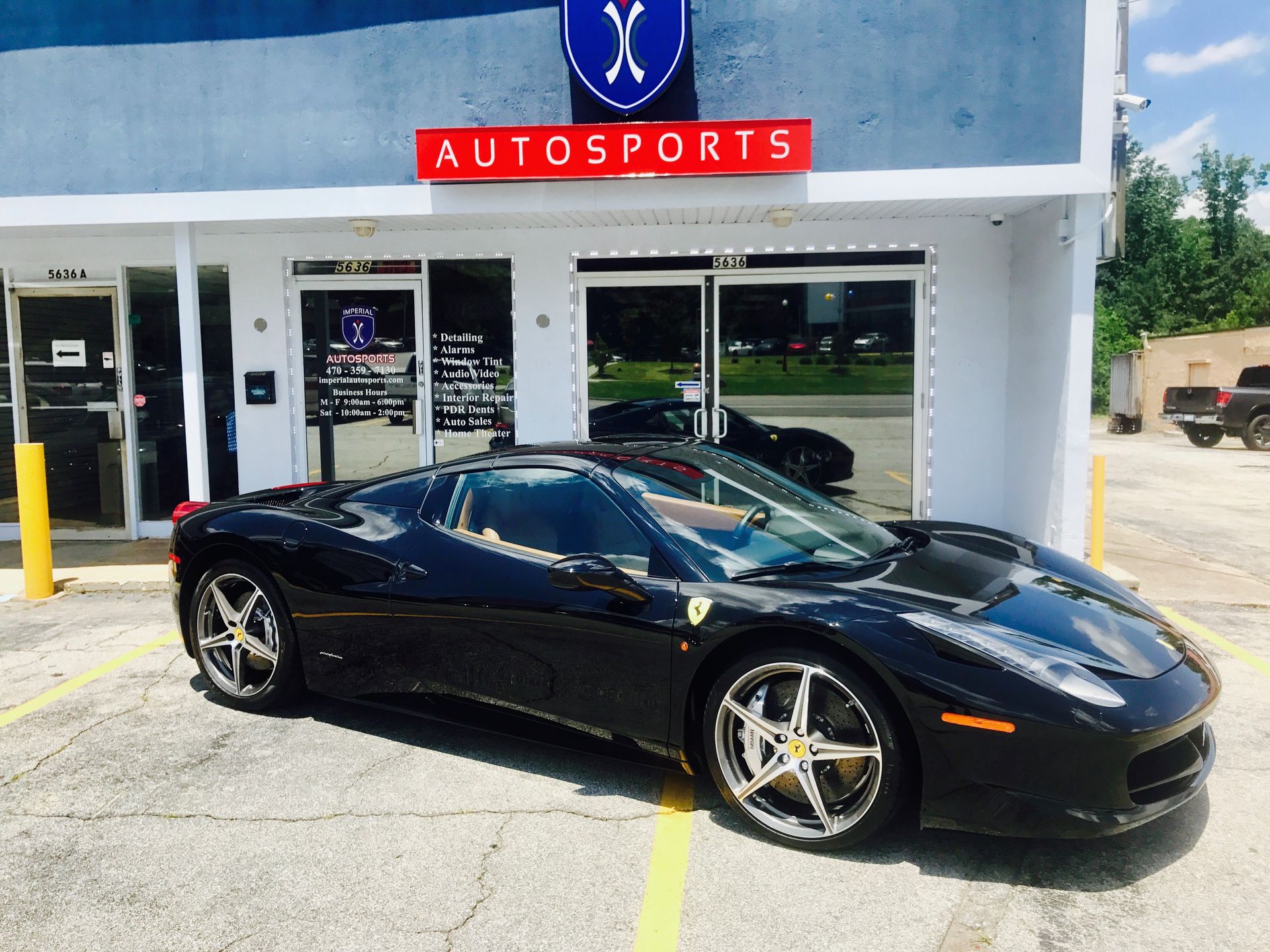 A black sports car is parked in front of an Autosports store