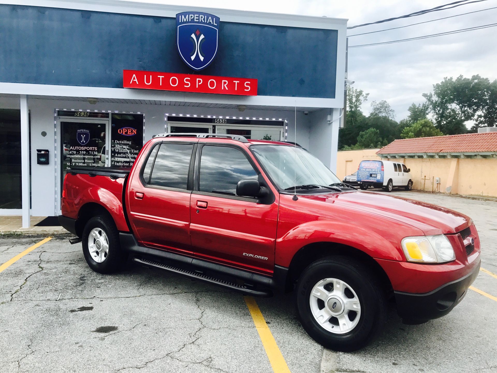 A red pickup truck is parked in front of an auto sports store