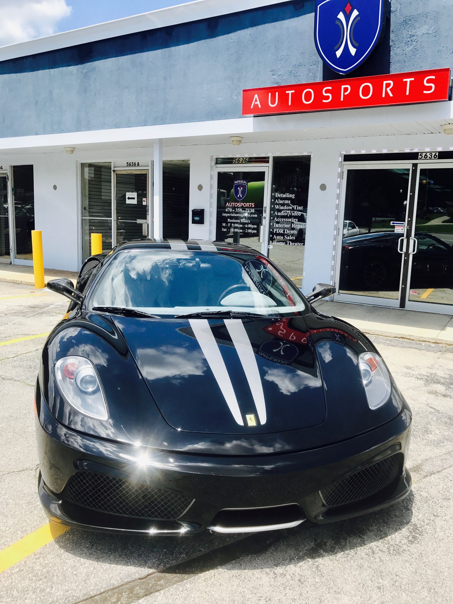 A black sports car is parked in front of an autosport store