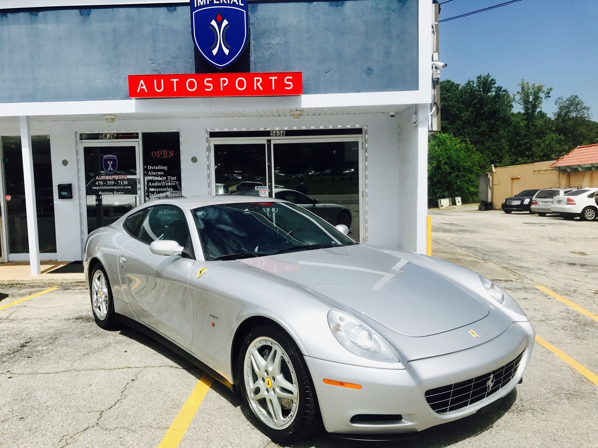 A silver sports car is parked in front of a building that says Autosports