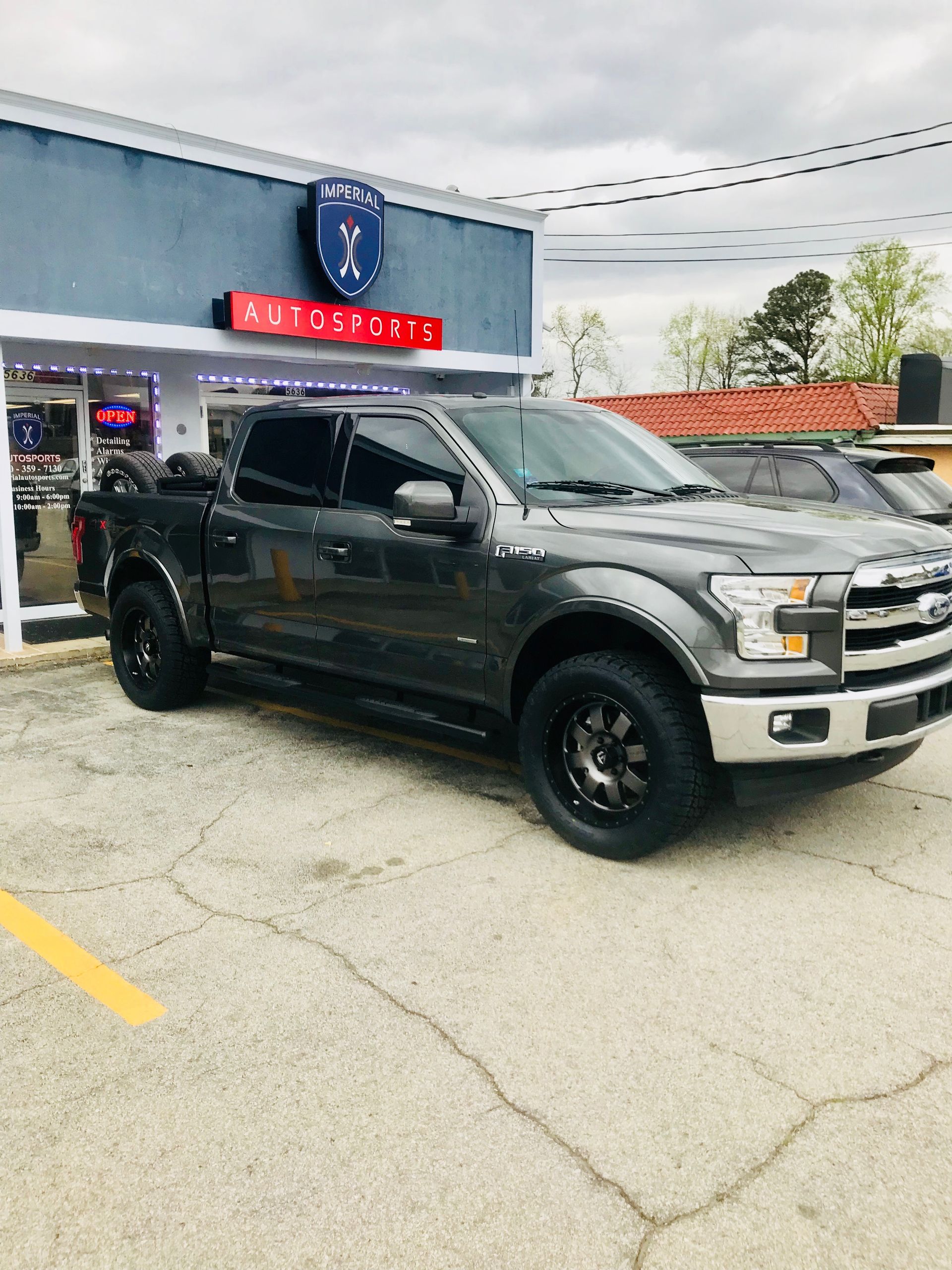 A black truck is parked in front of a car dealership