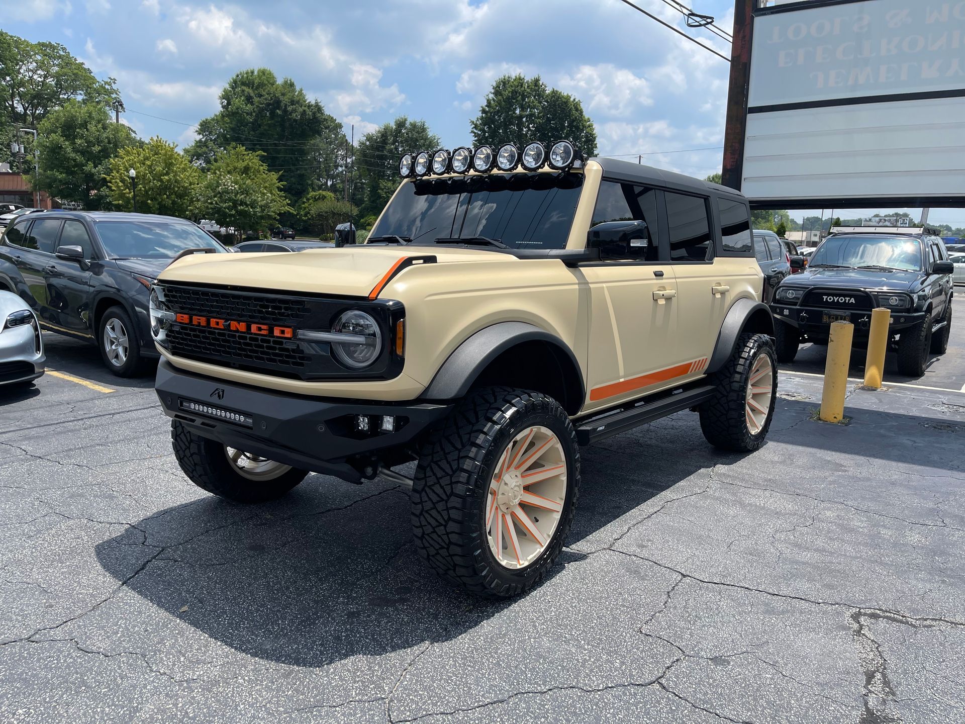 A tan Ford Bronco is parked in a parking lot.