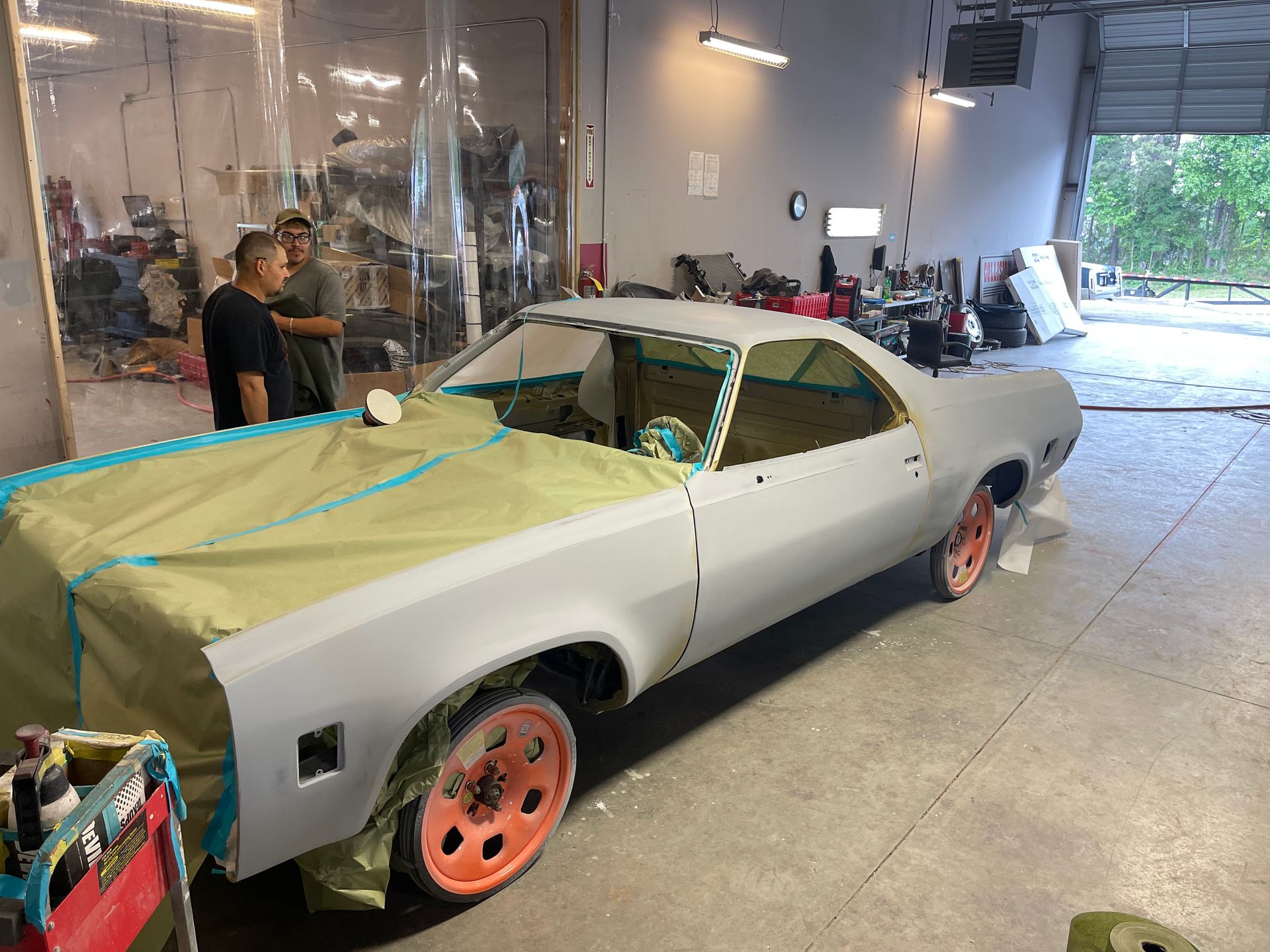 A white car is being painted in a garage