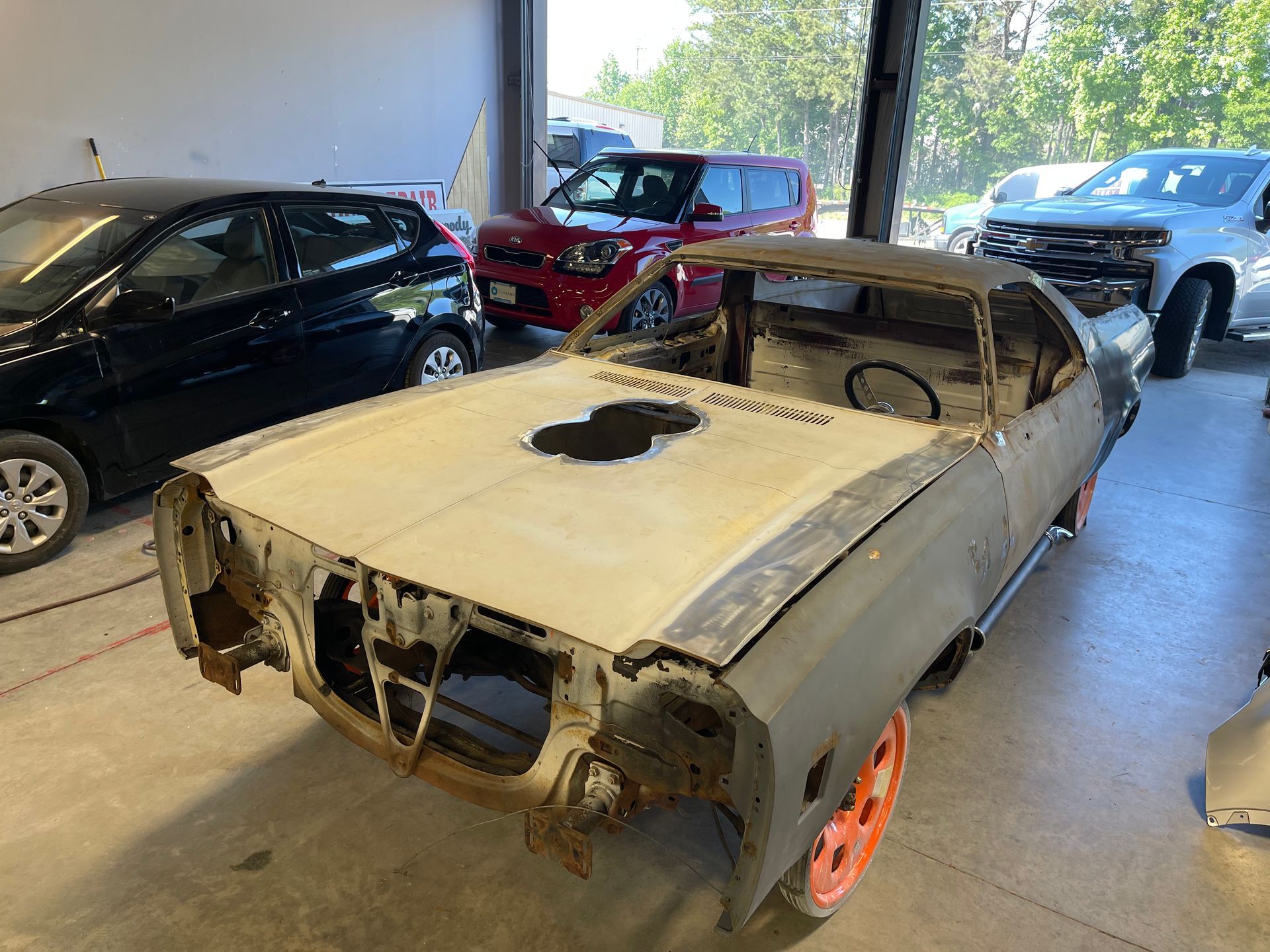 A car is sitting in a garage with a hole in the hood