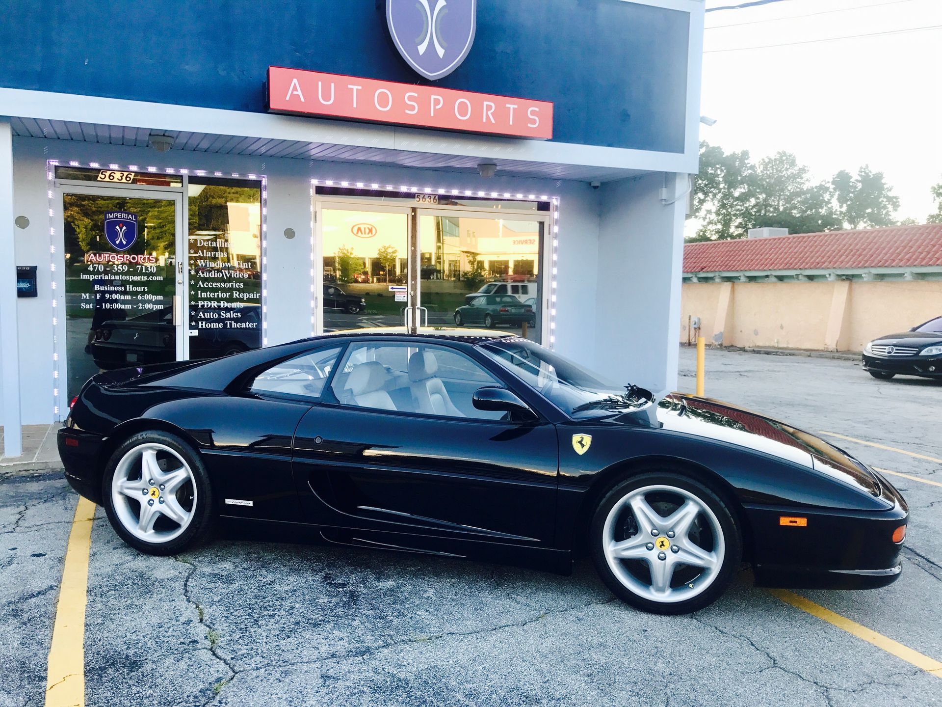 A black sports car is parked in front of an auto sports store