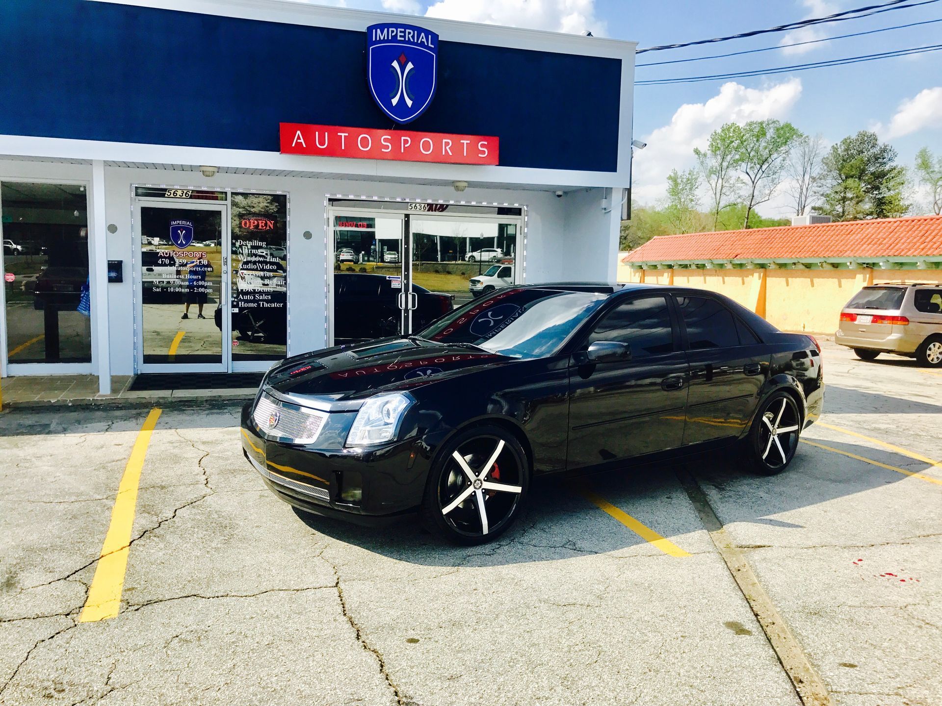 A black car is parked in front of a car dealership