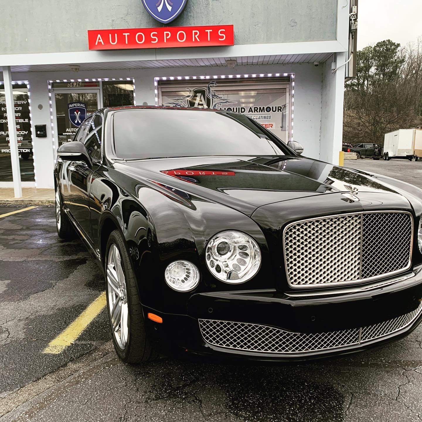 A black Bentley is parked in front of Autosports