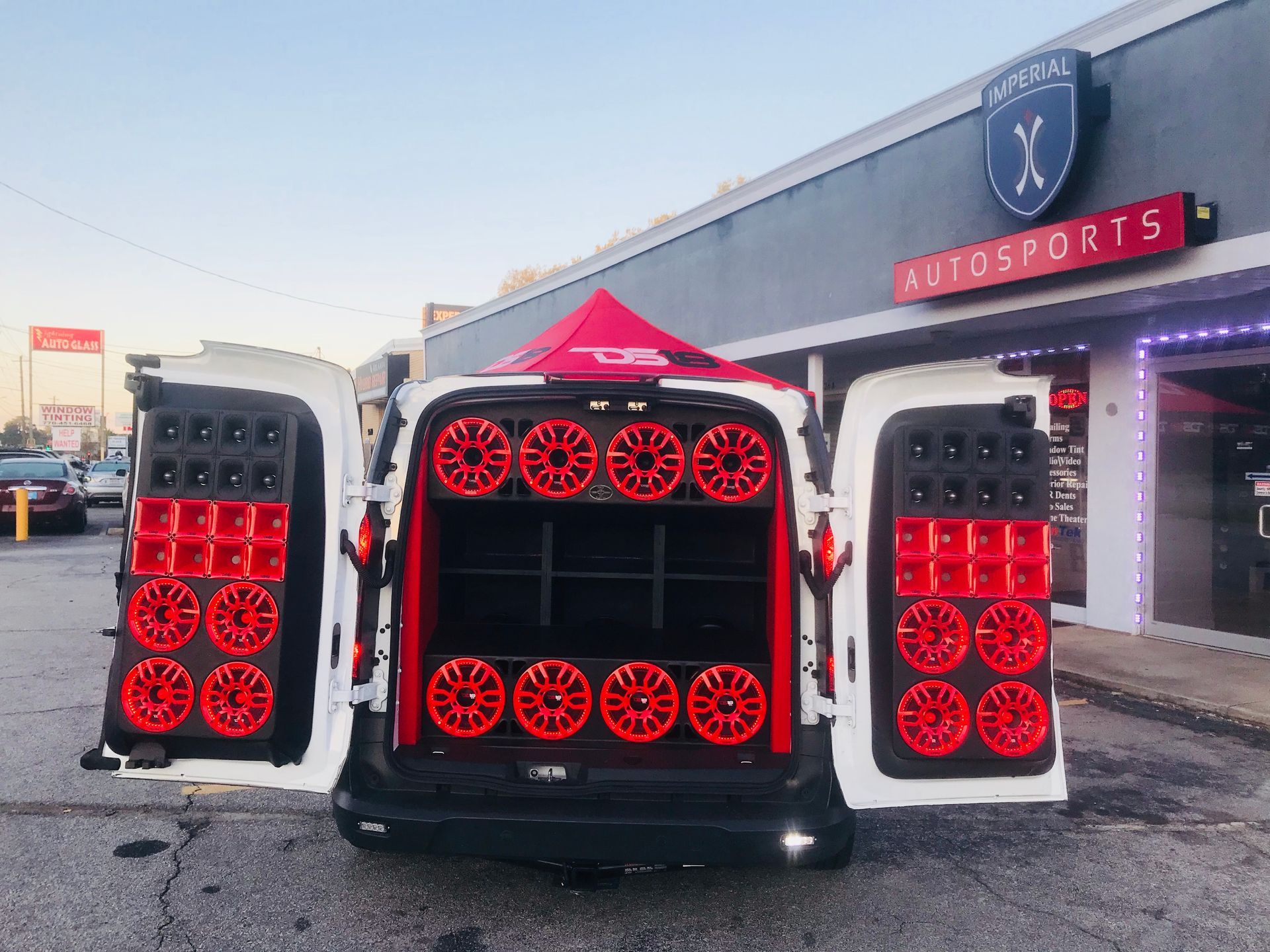 A white van is parked in front of a store called Autosports