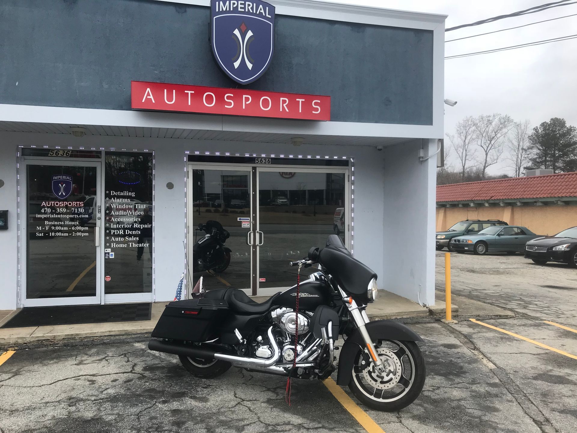 A motorcycle is parked in front of a store called Imperial Autosports
