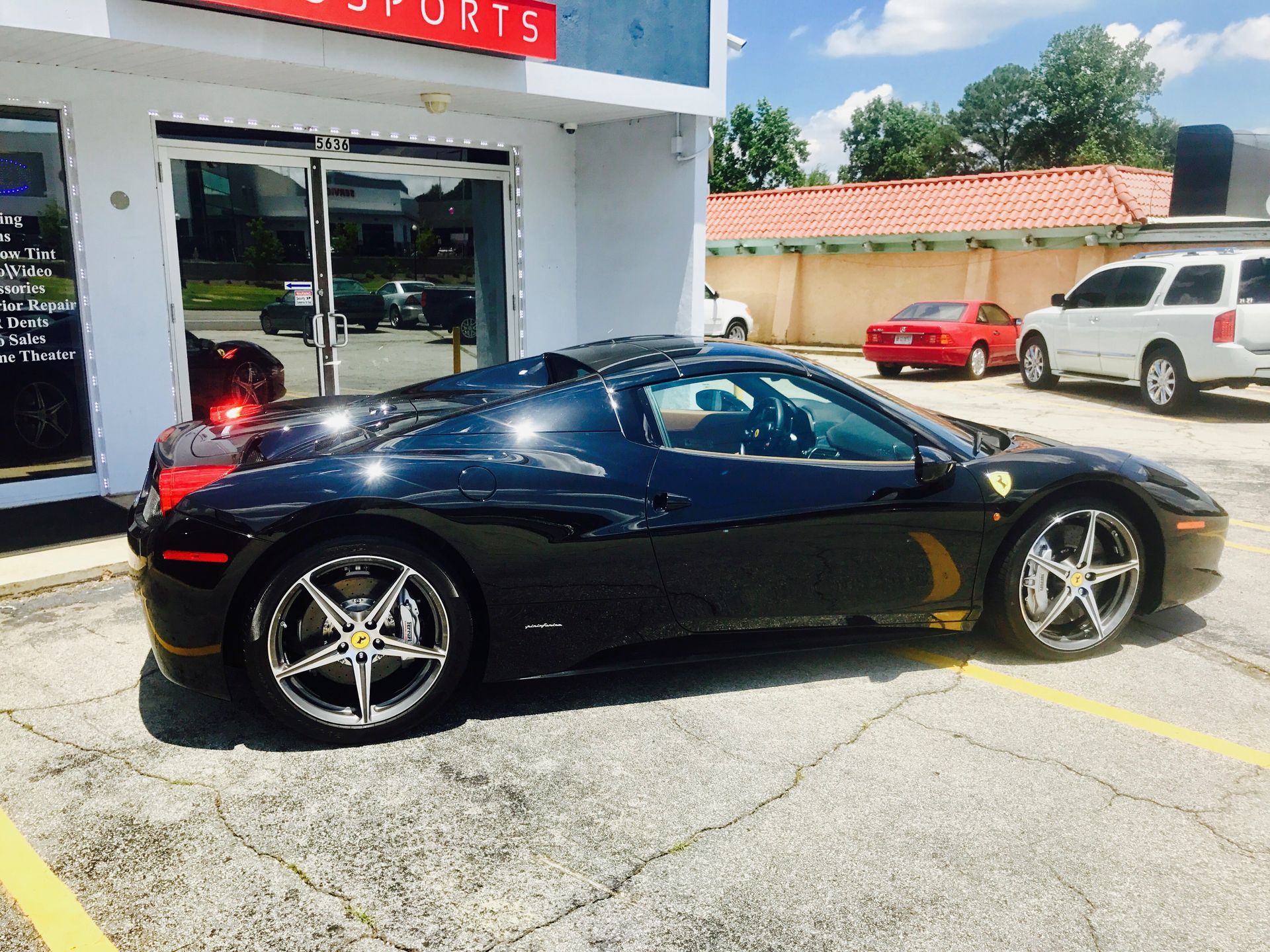 A black sports car is parked in front of a store