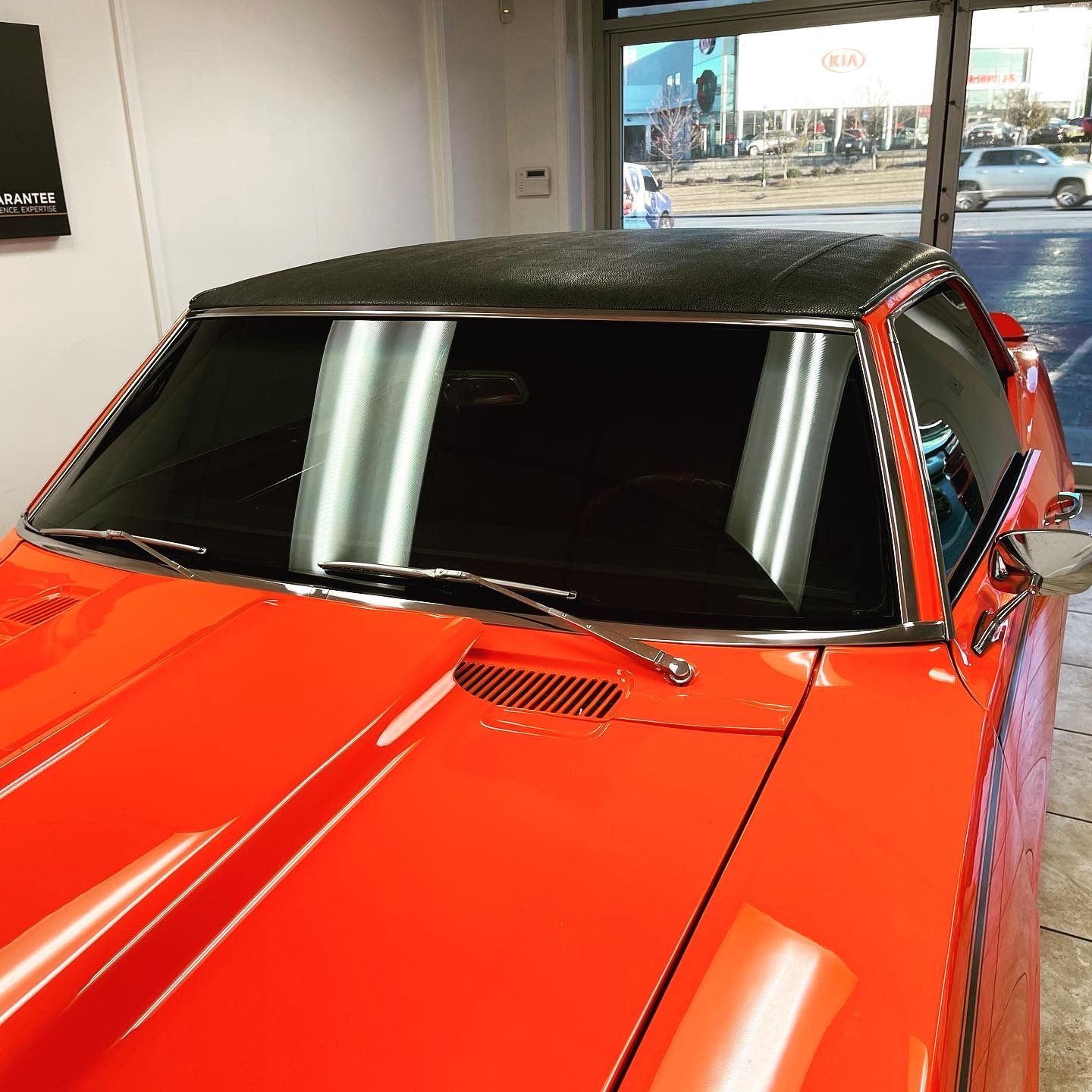A red car with a black roof is parked in a garage
