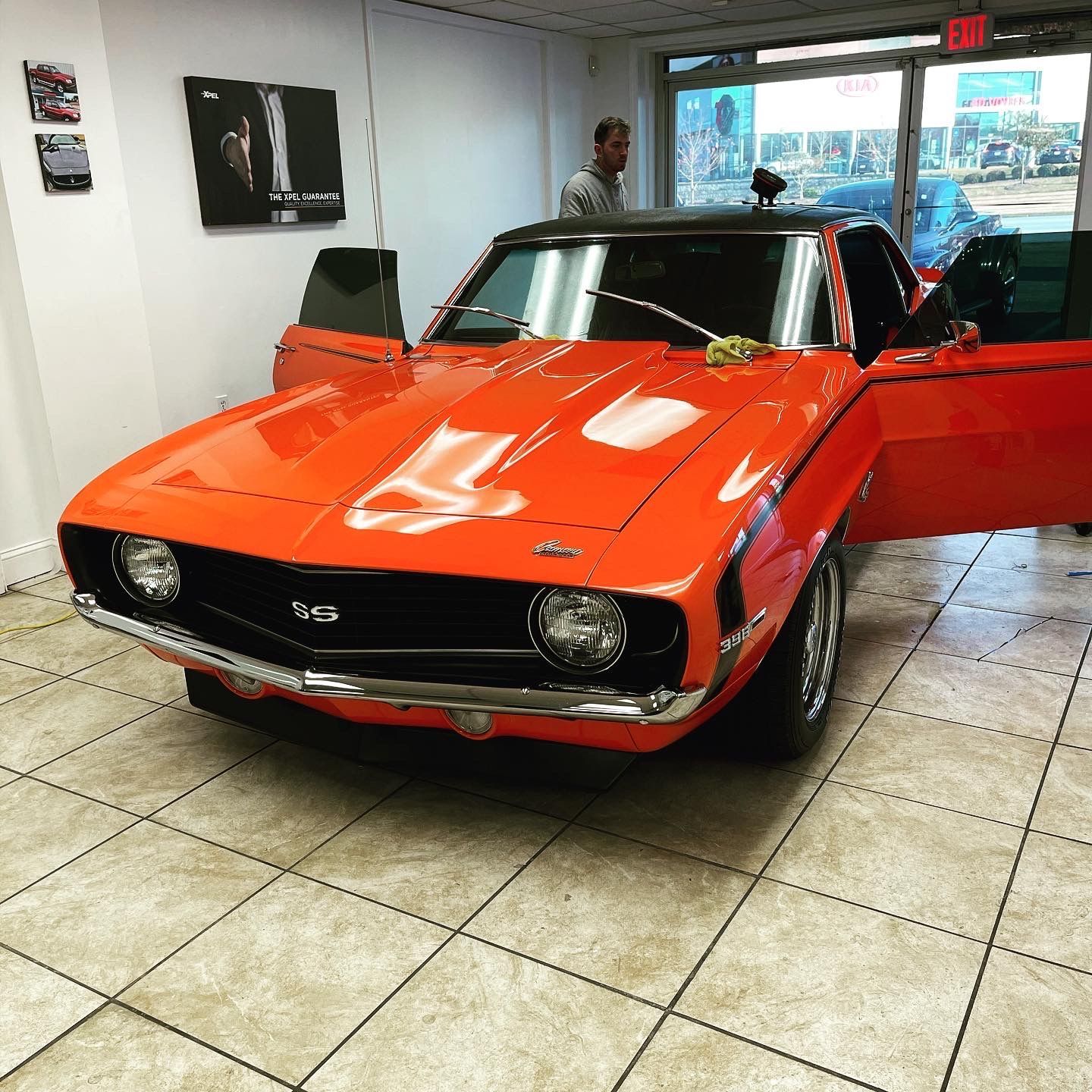 An orange Chevrolet Camaro is parked in a garage with its doors open