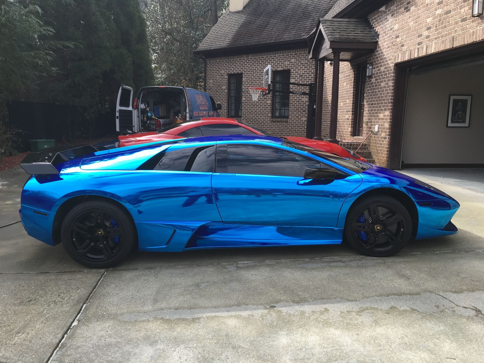 A blue Lamborghini is parked in front of a brick house