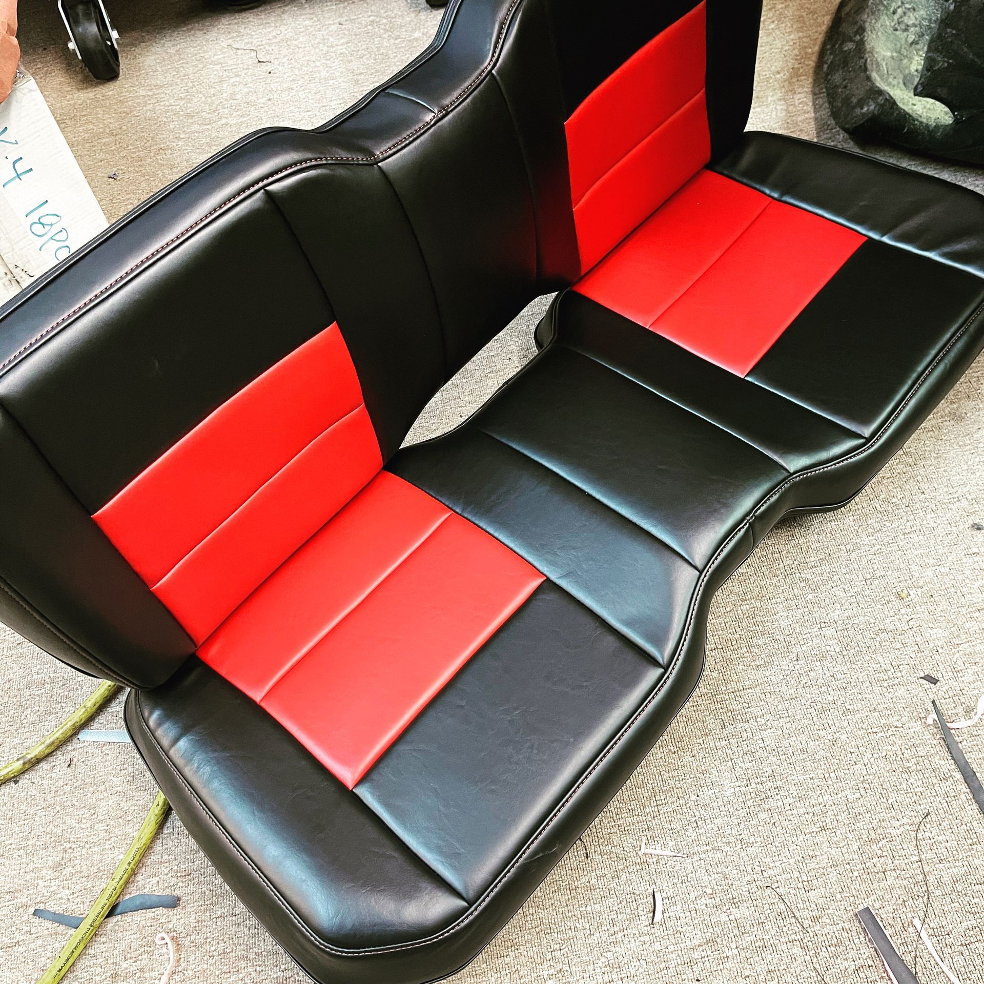 A black and red seat is sitting on a carpeted floor