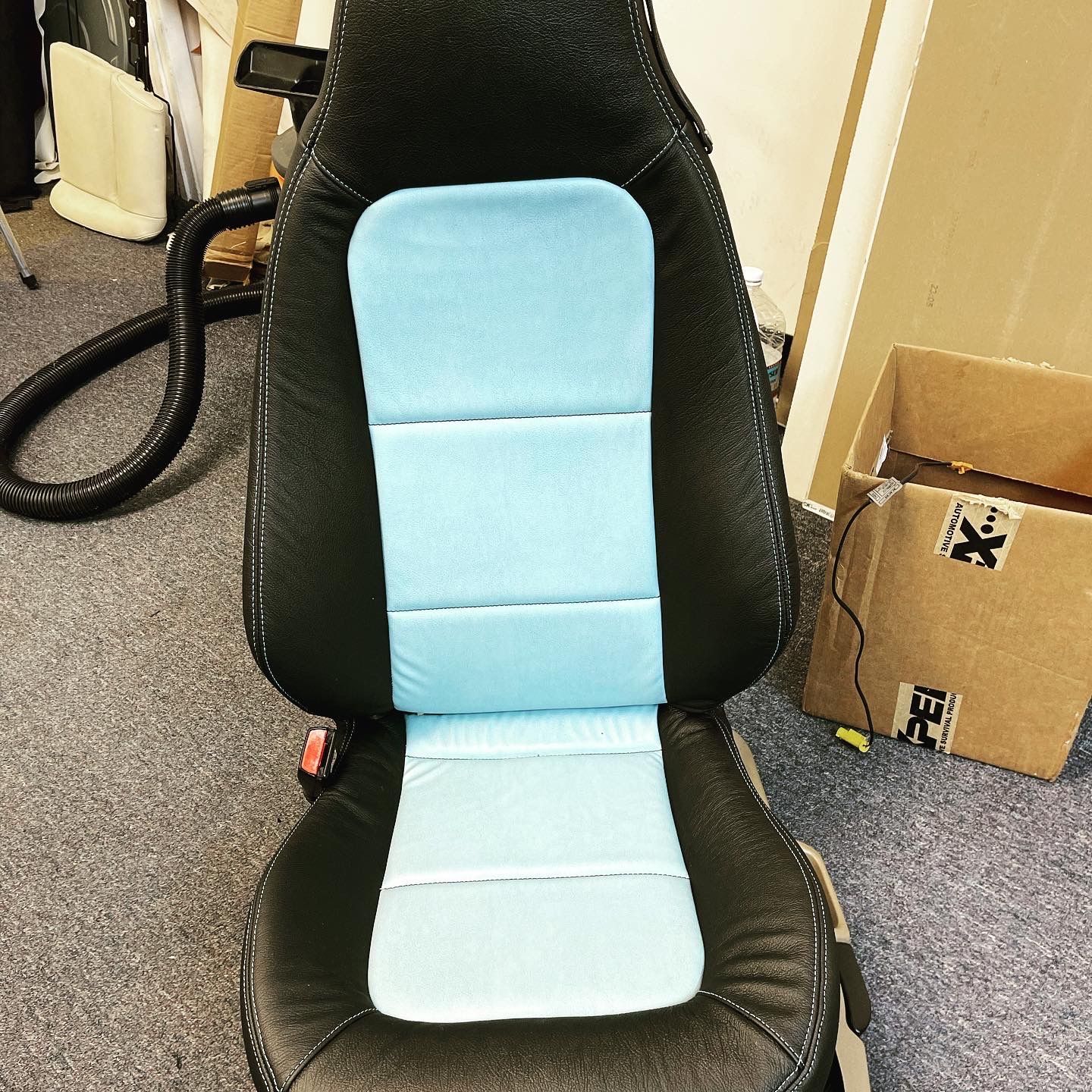 A black car seat with a blue cushion on it