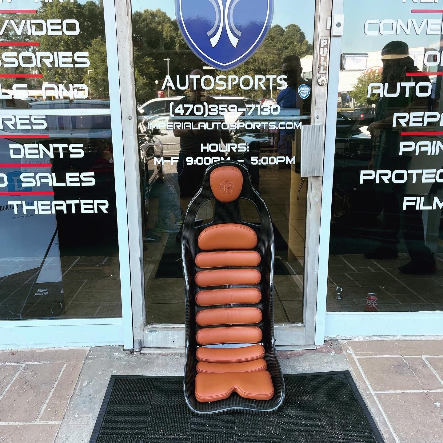 A racing seat sits in front of a store called Autosports