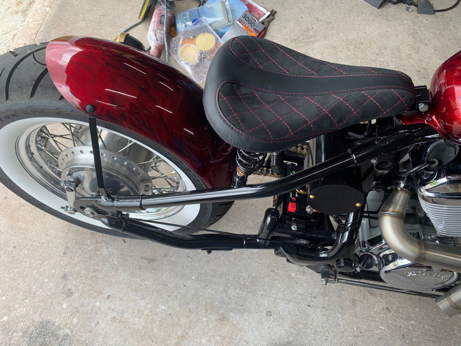 A red motorcycle with a black seat is parked in a garage