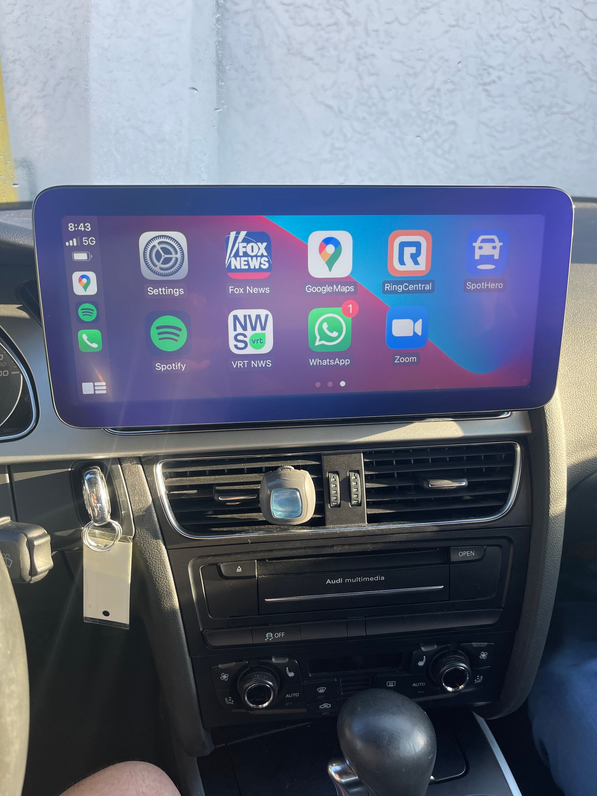 A person is sitting in a car with a tablet on the dashboard