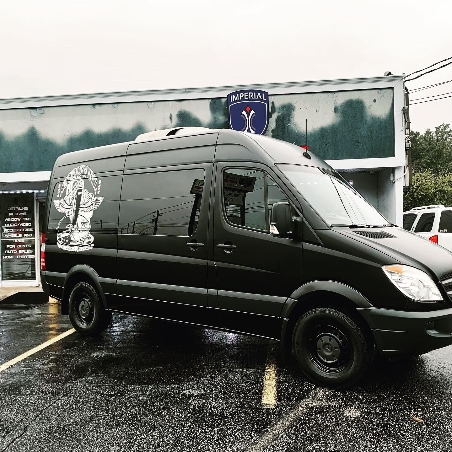 A black van is parked in front of a building