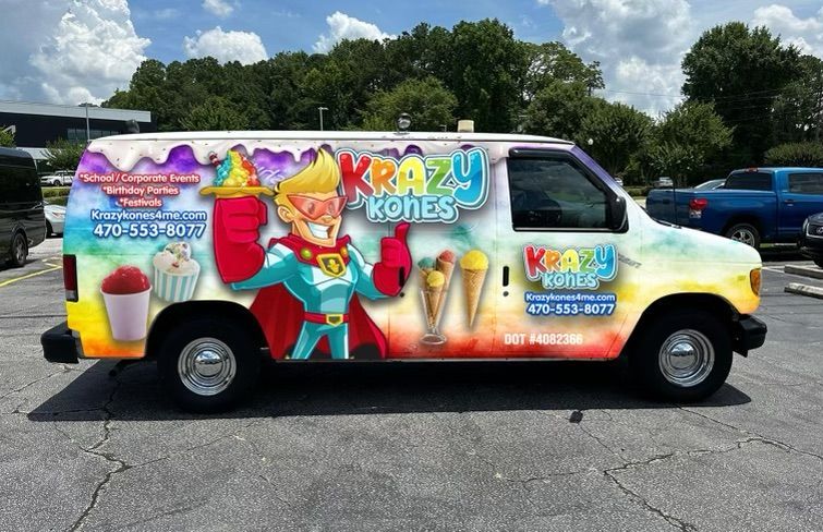 A van with a superhero on the side is parked in a parking lot