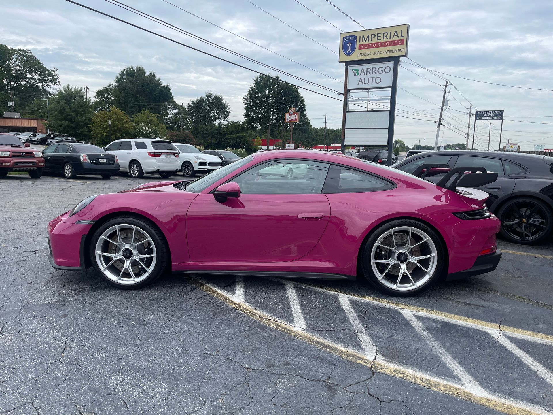 A pink Porsche 911 gt3 is parked in a parking lot