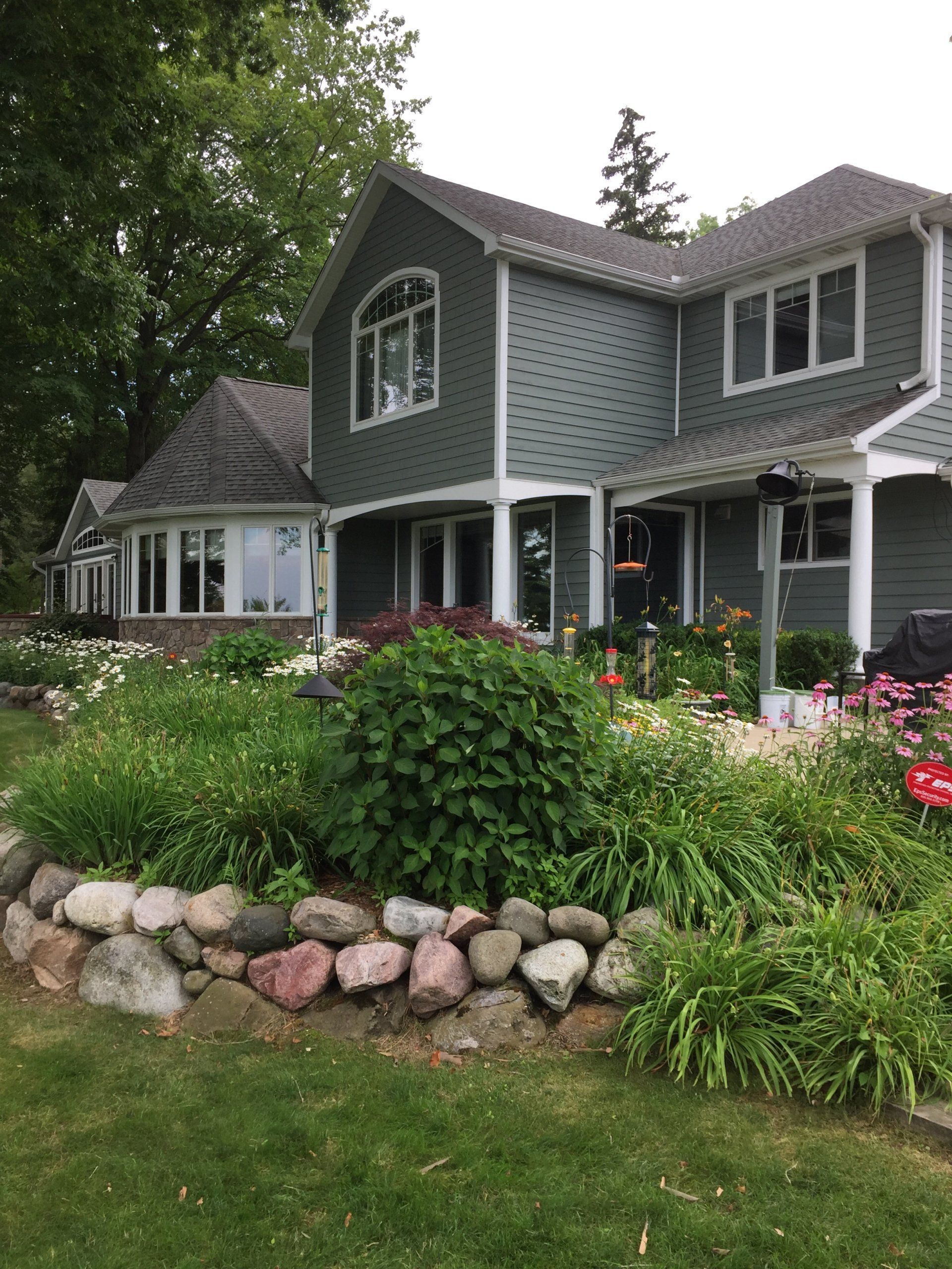 Green house with a rock garden and white trim.