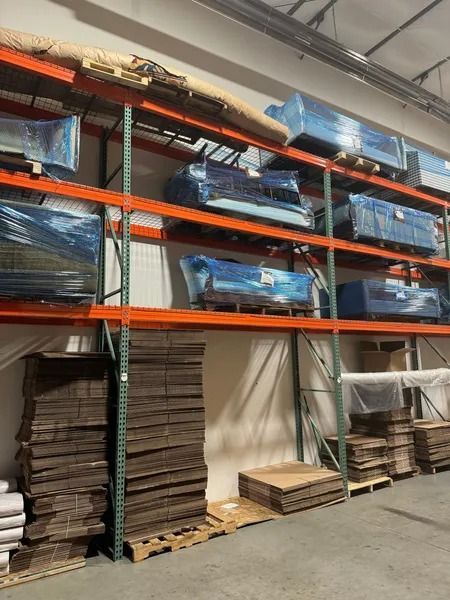 Shelving in a warehouse with blue-wrapped items and cardboard stacks.