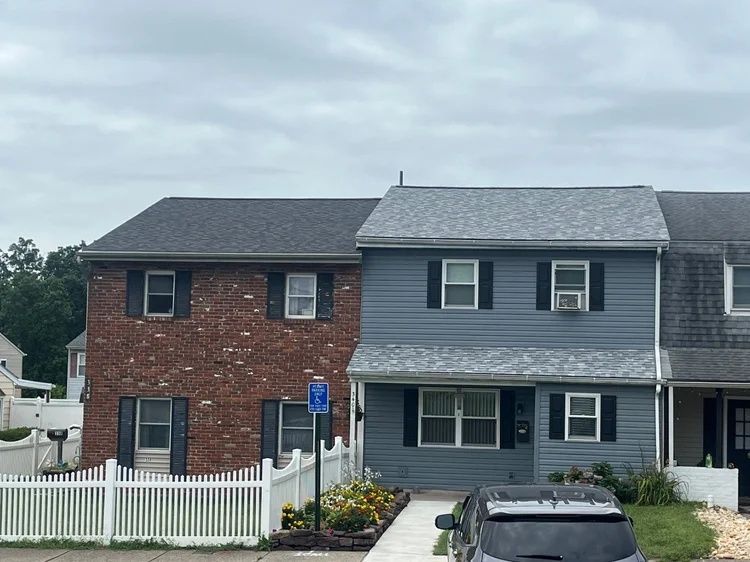 Row of townhouses with white fence, gray and brick facades, and parked car in front