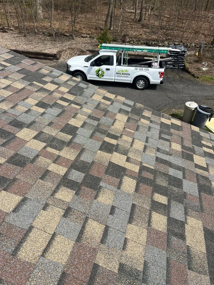 White utility truck parked on a patterned brick driveway beside a lawn and stacked materials.