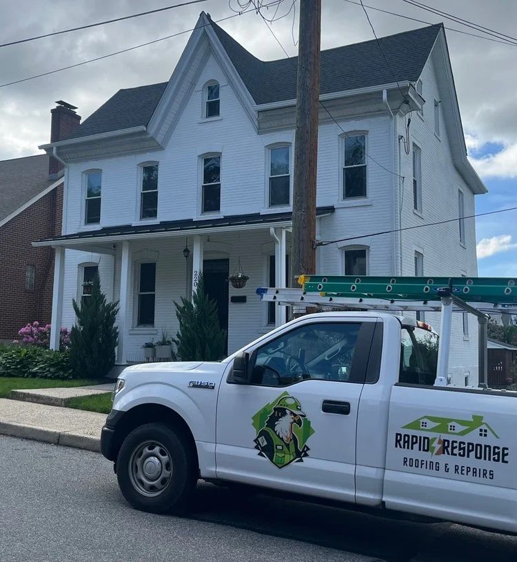 White two-story house with a utility truck parked in front and a utility pole beside it.