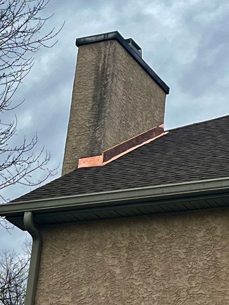 House chimney with visible brick damage near the roofline under a cloudy sky